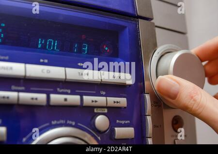 Controllo manuale del volume nel Music Center. La mano di una donna regola in primo piano il volume sul Music Center Foto Stock