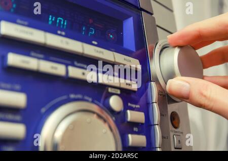 Controllo manuale del volume nel Music Center. La mano di una donna regola in primo piano il volume sul Music Center Foto Stock