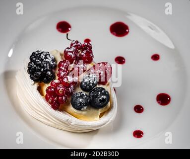 Deliziosa torta con frutti di bosco: Ribes rosso, mirtilli, more. Crema e bella forma. Dessert nel ristorante. Cibo. Isolato su nero ba Foto Stock