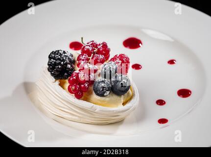 Deliziosa torta con frutti di bosco: Ribes rosso, mirtilli, more. Crema e bella forma. Dessert nel ristorante. Cibo. Isolato su nero ba Foto Stock