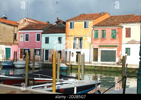 Venezia, isola di Burano, vista di un canale nel pomeriggio luce, cielo luminoso e scuro dopo una tempesta, tradizionale veneziana dipinta facciate riflessione Foto Stock