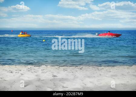 Attività acquatiche marine all'aperto. Cavalcando una banana nell'oceano su un cavo usando una barca a motore, spazio di copia. Sport acquatici in mare. Foto Stock