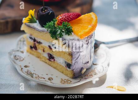 Primo piano fetta torta di frutta compleanno in piatto violetto delizioso crema in strato Foto Stock