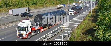 Guardando verso il basso sul carico del cilindro lungo di grandi dimensioni trasporto di autocarri e autocarri con rimorchio con caricatore basso che ne occupa due Corsie autostrada M25 Inghilterra Regno Unito Foto Stock