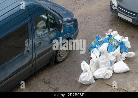 Sacchetti di detriti di costruzione, miscele di costruzione sul marciapiede vicino alla vettura Foto Stock