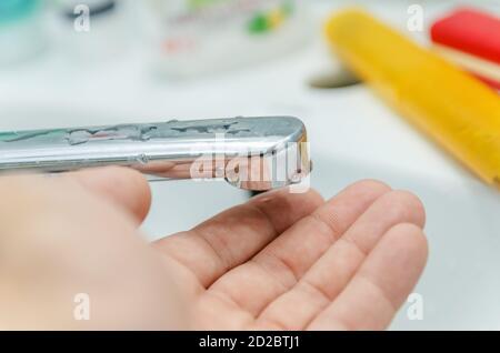 Primo piano dell'uomo messo la mano sotto il rubinetto, l'acqua non scorre. Foto Stock