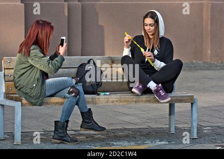 Zrenjanin, Serbia, 05 ottobre 2019. Due ragazze, studenti, stanno riposando su una panchina nel centro della città. Godono di una bella giornata piacevole e di aria fresca. Foto Stock