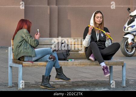 Zrenjanin, Serbia, 05 ottobre 2019. Due ragazze, studenti, stanno riposando su una panchina nel centro della città. Godono di una bella giornata piacevole e di aria fresca. Foto Stock