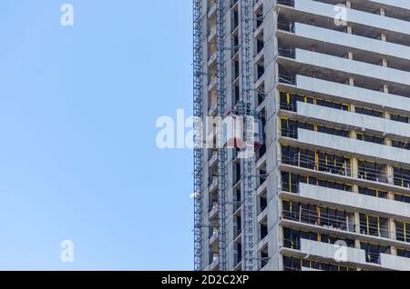 Costruzione di un edificio residenziale a più piani. Ascensore per il trasporto merci di sollevamento presso il cantiere Foto Stock