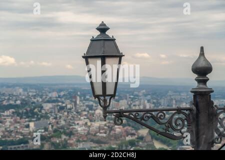 Primo piano lampada da strada con lo sfondo su Tbilisi da Mount Mtantsminda nel tempo regionale Foto Stock