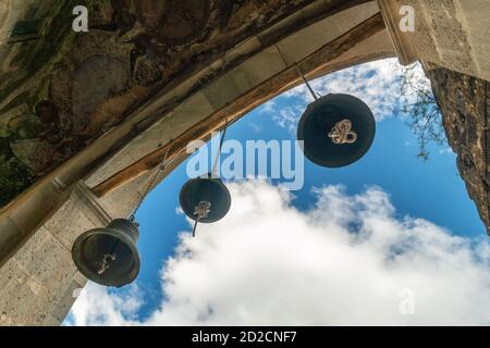 tre campane nella chiesa per le lingue catturati le corde delle campane, sullo sfondo del cielo nuvoloso Foto Stock