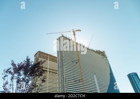 Costruzione di edifici a più piani a Batumi. Gru di costruzione sullo sfondo degli edifici. Edificio a piani contro il cielo blu. Foto Stock