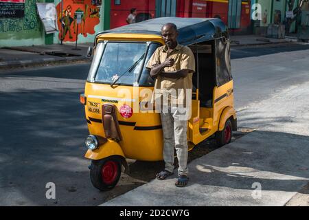 Chennai, India - 6 febbraio 2020: Un tassista non identificato in posa davanti al suo risciò auto giallo tradizionale il 6 febbraio 2020 Foto Stock