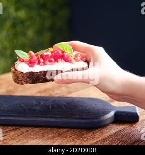 La donna tiene la bruschetta, colazione italiana in un caffè estivo Foto Stock