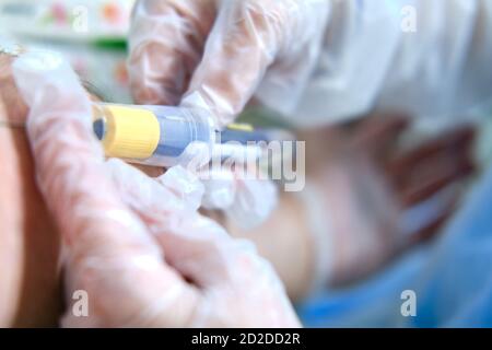 Il medico prende il sangue con una siringa dalla vena di un uomo con una covide, primo piano Foto Stock