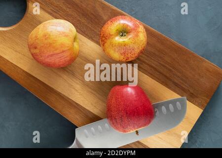 Due belle mele rosse e un coltello sul tagliere. Foto Stock