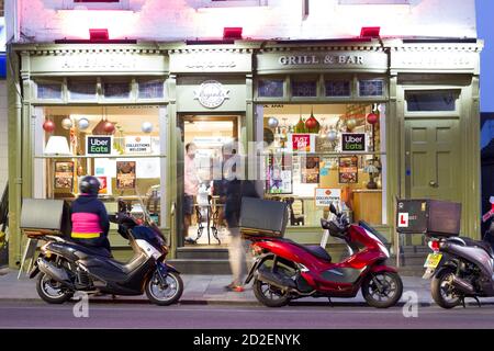 Grill & bar che dà fuori gli ordini del take away all'uomo di consegna durante la limitazione di lockdown di Covid19 a Greenwich, Greater London, England Foto Stock