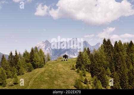 Piccolo rifugio appartato per i pastori sulle Alpi Italiane. Paesaggio delle Dolomiti, un prato verde e cielo nuvoloso sulla cima della montagna vicino ad Agordo Foto Stock