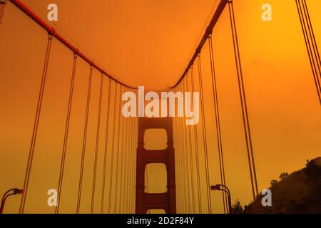 Vista dal basso del cielo arancione fumoso sul Golden Gate Bridge della città di San Francisco dalla vista dal basso. Incendi in California negli Stati Uniti d'America Foto Stock