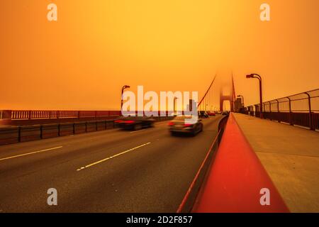 Auto che attraversano il Golden Gate Bridge dal Presidio a nord. Smoky Orange cielo il ponte della città di San Francisco per gli incendi della California in America Foto Stock