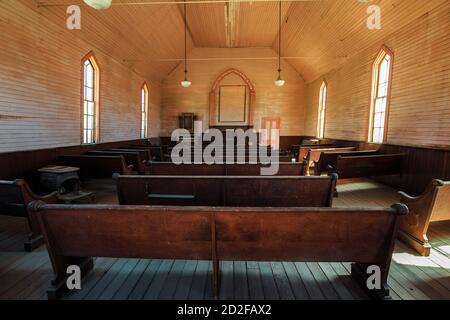 Bodie state Historic Park, California, Stati Uniti d'America - 12 agosto 2016: Chiesa Metodista interno con antiche panchine e altare a Bodie Foto Stock