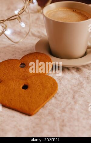 Colpo verticale di una tazza di caffè e biscotti a forma di cuore Foto Stock