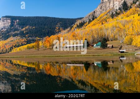 A cabin reflects a scenic autumn landscape in the water of a calm mountain lake near Durango, Colorado, USA Foto Stock