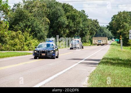 Florida, Mabel, state Road Route 50, strada a due corsie, oversize oversize oversize load adapprossima, scorta auto della polizia, traffico di compensazione, luce lampeggiante barra luminosa, vi Foto Stock