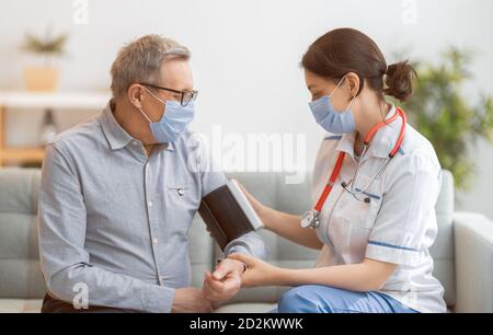 Paziente anziano e medico che misura la pressione sanguigna. Foto Stock