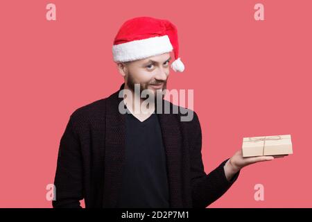 Primo piano foto di un uomo generoso con cappello di santa e la barba che tiene un regalo e sorridi con la fotocamera abbigliamento casual Foto Stock