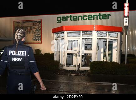 Dorsten, Germania. 07 ottobre 2020. Una donna di polizia si trova di fronte ad un distributore di contanti soffiato, che si trova in un padiglione indipendente nel parcheggio di fronte ad un centro giardino in un parco industriale. Le finestre del padiglione sono frantumate, la porta è appesa storta nelle cerniere. Persone sconosciute hanno fatto esplodire due macchine di cassa a Essen e Dorsten. L'esplosione a Dorsten si è verificata poco dopo le 2 del mercoledì, ha detto un portavoce della polizia. I testimoni hanno osservato dopo il crimine, come qualcuno è fuggito in una macchina oscura. Credit: Bludau Foto/dpa/Alamy Live News Foto Stock