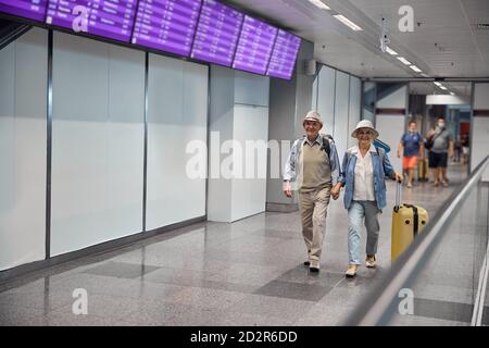 Una gioiosa coppia sposata camminando lungo il terminal dell'aeroporto Foto Stock