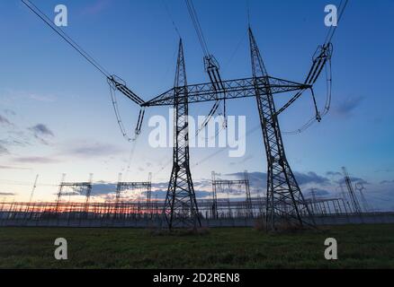 Alta tensione polo elettrico e linee di trasmissione della sera. Tralicci di energia elettrica al tramonto. Potenza ed energia. La conservazione dell'energia. Tensione alta gr Foto Stock