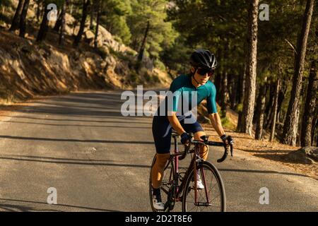 donna matura allenamento bici da strada, arrampicata su una strada di montagna, vista frontale Foto Stock