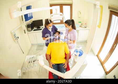 Dentista e assistente che tiene gli strumenti per curare i denti del paziente Foto Stock