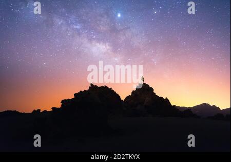Silhouette di uomo di escursionisti in piedi su roccia scura contro Cielo stellato notturno a lunga esposizione a Tenerife Foto Stock