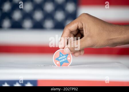 Primo piano di mani che ho votato adesivo precoce all'interno della casella di voto - concetto di voto precoce in noi elezioni. Foto Stock