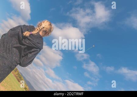 ragazza carina che corre con aquiloni in campo verde in sole giorno autunnale Foto Stock