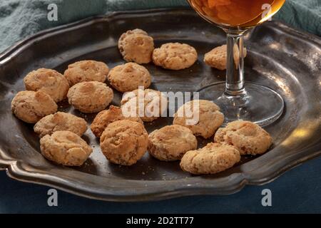 Amaretti, biscotti tradizionali italiani alle mandorle, con un bicchiere di liquore dolce, un primo piano Foto Stock