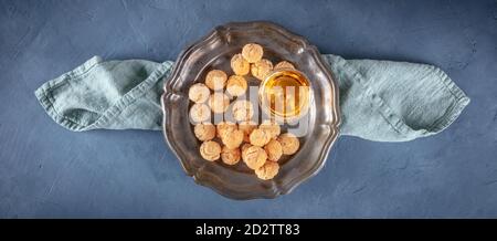 Vista dall'alto di Amaretti, biscotti tradizionali italiani alle mandorle, con liquore amaretto, panorama a cielo con spazio copia, su sfondo blu scuro Foto Stock