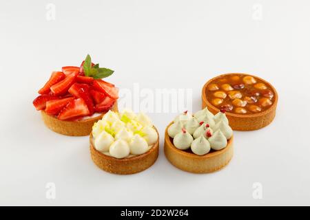 Set di quattro mini crostate con lamponi, crema e nocciola su sfondo bianco Foto Stock