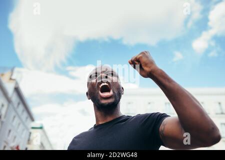 uomo che protesta a un raduno per l'uguaglianza razziale che alza le armi. Le vite nere contano. Foto Stock