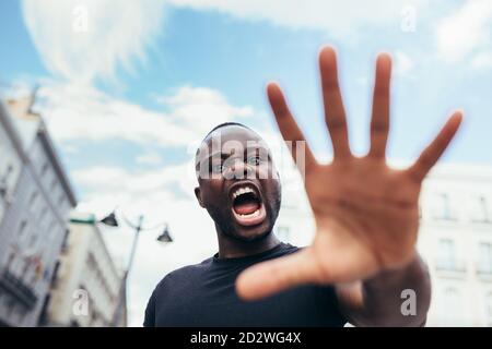 uomo che protesta ad un raduno per l'uguaglianza razziale che alza le braccia mostrando mano alla macchina fotografica. Le vite nere contano. Foto Stock