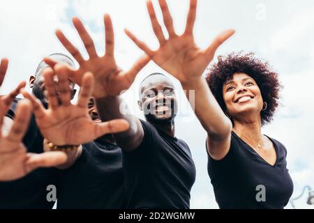 Allegri uomini neri e Donna alzando le mani contro un cielo blu Foto Stock