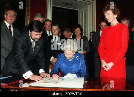 La Regina firma i libri dei visitatori delle tre Queen's Colleges in Irlanda mentre il presidente irlandese Mary Robinson guarda durante un ricevimento al St James's Palace, nel centro di Londra. La reception si è tenuta in occasione del Sesquicentenario dei Queen's Colleges in Irlanda. Foto Stock