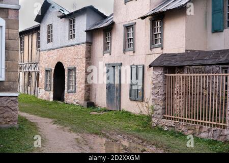 Strada della città vecchia con bar sulle finestre, porte in legno e un puddle sulla strada Foto Stock