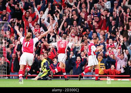 QUESTA IMMAGINE PUÒ ESSERE UTILIZZATA SOLO NEL CONTESTO DI UNA FUNZIONE EDITORIALE. Dennis Bergkamp di Arsenal (a destra) si gira dopo aver segnato il suo primo gol al fianco durante la partita di oggi (domenica) della fa Carling Premiership contro Newcastle United a Highbury. Un guardiano di Forlorn Newcastle Shay Gived (2° a sinistra) guarda come i compagni di squadra di Bergkamp Emmanuel Petit (a sinistra) e Lee Dixon si uniscono alle celebrazioni. (Punteggio finale Arsenal 3 Newcastle United ). Foto di Tom Hevezi/PA. Foto Stock