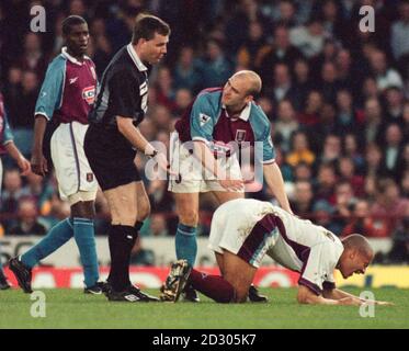 Questa immagine può essere utilizzata solo nel contesto di una funzione editoriale. West Ham United e England Defender Rio Ferdinand è ferito in un incidente fuori palla con Mark Draper di Aston Villa durante una partita di calcio fa Premiership a Villa Park. * arbitro G Willard, si prepara a distribuire una carta gialla a Draper. Foto Stock