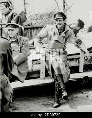 Sir Dirk Bogarde, con trench coat, maschera a gas e leggings, durante la realizzazione del film 'Re e Paese'. Accanto a lui è il compagno attore Peter Copley (a sinistra). Sir Bogarde morì l'8 maggio 1999, all'età di 78 anni. Foto Stock