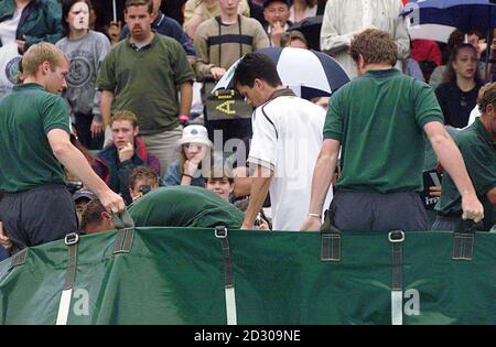 Il britannico No.1 Tim Henman (centro) lascia il campo uno dopo la pioggia ha interrotto la partita per la seconda volta durante il suo quarto finale di partita contro Cedric Pioline di Francia ai campionati di tennis di Wimbledon 1999. Foto Stock